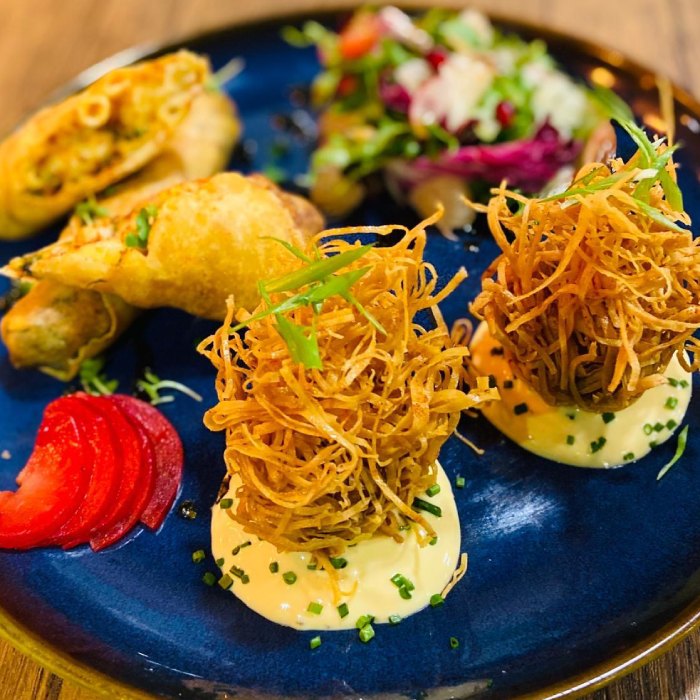 noodle fritters, spring rolls, salad, & pickled garnish served at Who’s 
Café. 